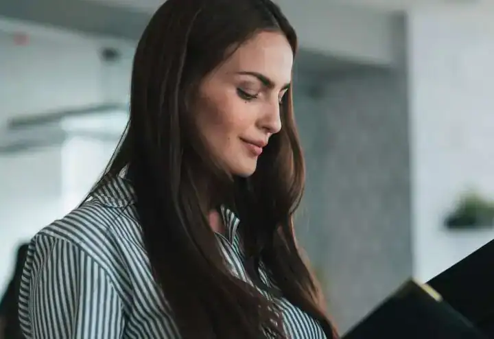 pexels-los-muertos-crew-10041279-720x494-jpg Gymnasiekvinna med långt brunt hår använder en surfplatta i en modern kontorsmiljö med fokus på bedömning och talangutvärdering.